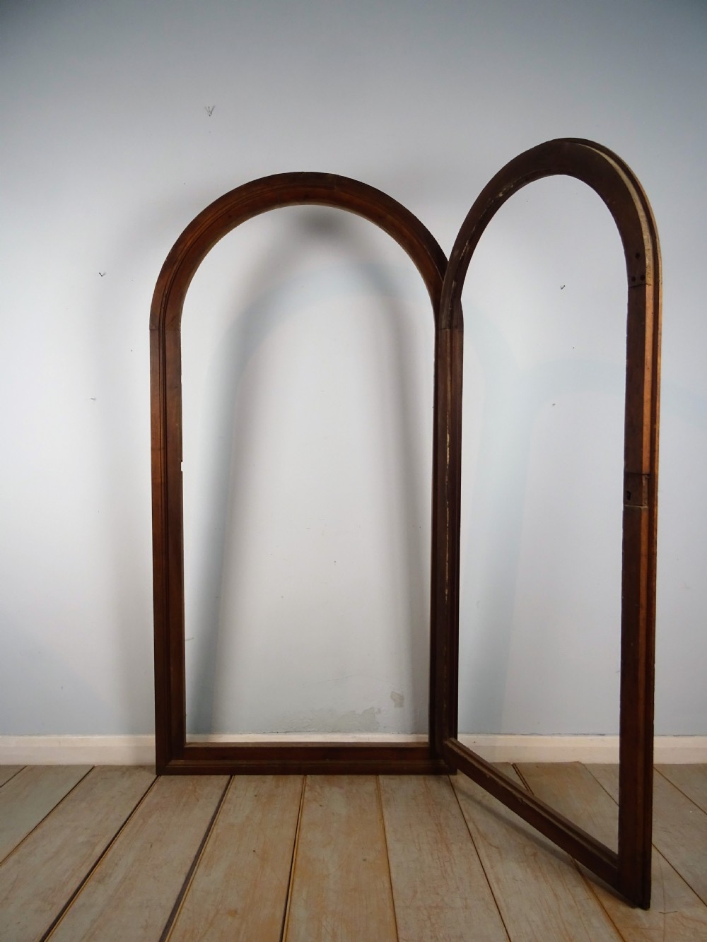 A group of three antique Italian walnut wooden door frames featuring rounded arches and moulded profiles. View XV