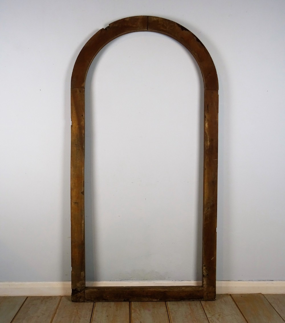 A group of three antique Italian walnut wooden door frames featuring rounded arches and moulded profiles. View IX