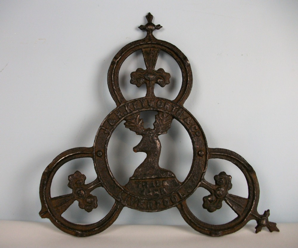 A dark cast iron trade sign featuring a central stag head within a circular ring flanked by trefoil motifs and raised lettering reading J & H Keyworth and Co Liverpool. View IV
