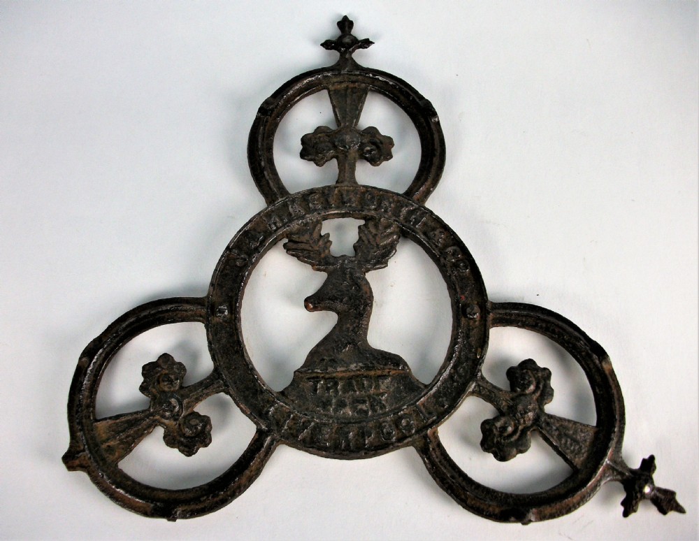 A dark cast iron trade sign featuring a central stag head within a circular ring flanked by trefoil motifs and raised lettering reading J & H Keyworth and Co Liverpool.