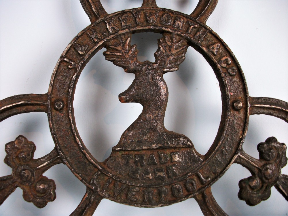 A dark cast iron trade sign featuring a central stag head within a circular ring flanked by trefoil motifs and raised lettering reading J & H Keyworth and Co Liverpool. View II