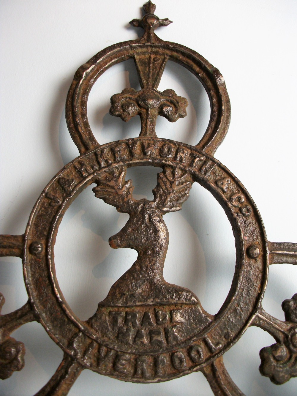 A dark cast iron trade sign featuring a central stag head within a circular ring flanked by trefoil motifs and raised lettering reading J & H Keyworth and Co Liverpool. View III
