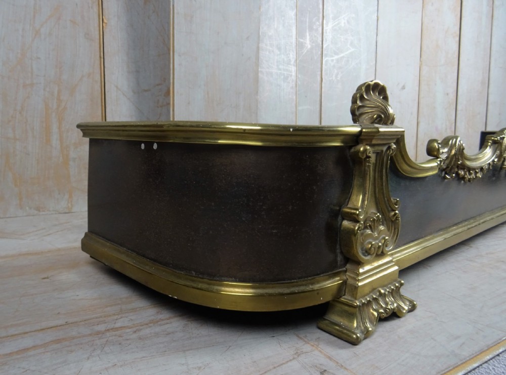 A 19th-century brass and dark steel fireplace fender featuring cast brass Rococo scrollwork and shell motifs along the top rail and corner feet. View IV