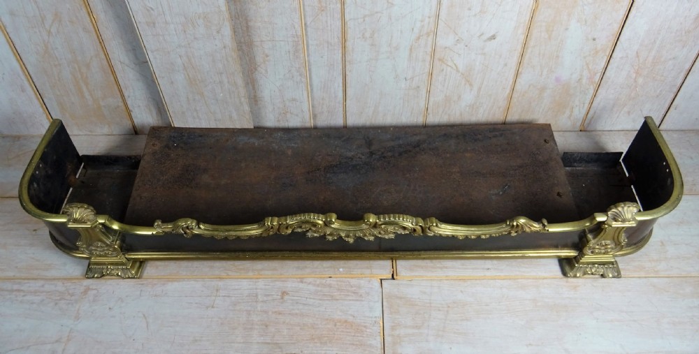 A 19th-century brass and dark steel fireplace fender featuring cast brass Rococo scrollwork and shell motifs along the top rail and corner feet. View II