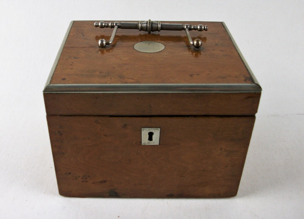A rectangular antique burr maple wooden tea caddy featuring metal trim, a lid handle, an oval central cartouche, and a keyhole escutcheon. View XI