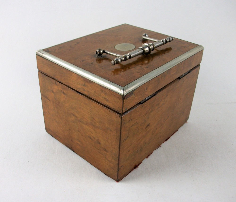 A rectangular antique burr maple wooden tea caddy featuring metal trim, a lid handle, an oval central cartouche, and a keyhole escutcheon. View VIII