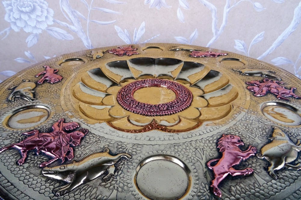 A circular engraved brass tray table with copper reliefs set upon a folding wooden base with a matching brass ewer and goblets. View III