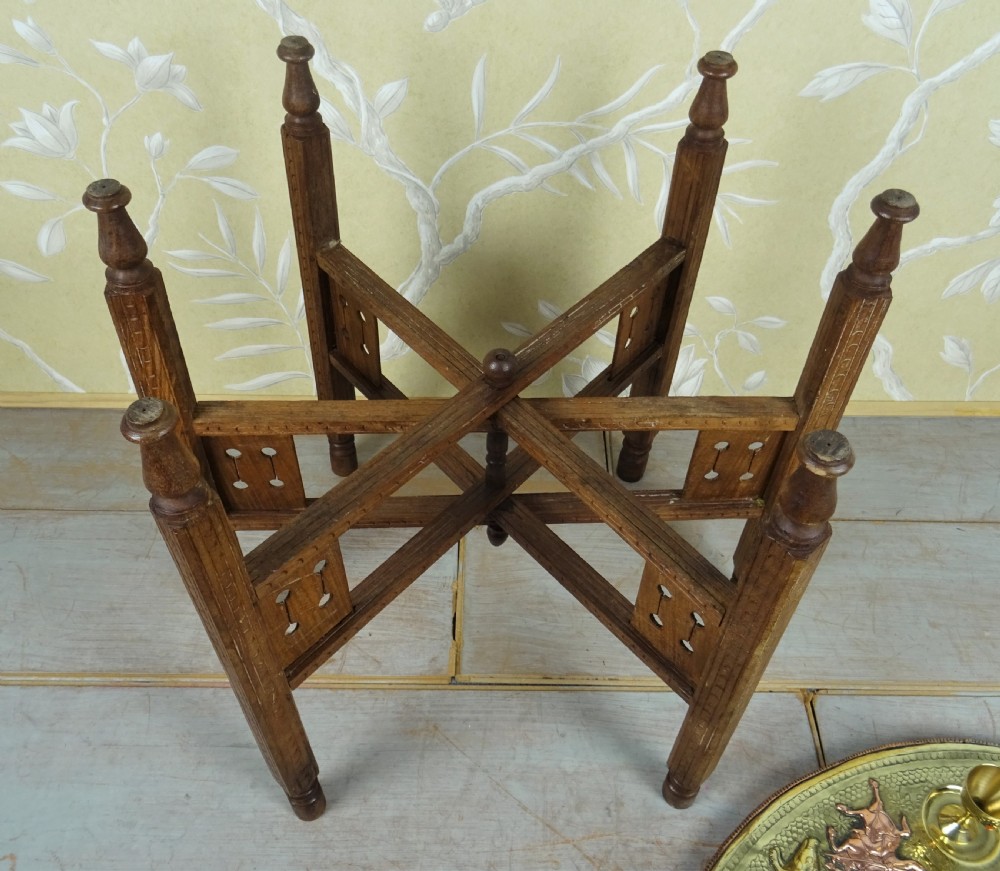 A circular engraved brass tray table with copper reliefs set upon a folding wooden base with a matching brass ewer and goblets. View VIII