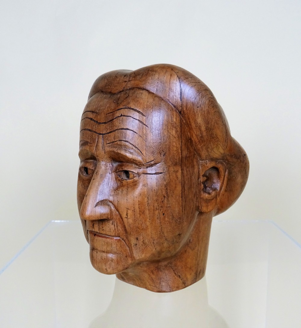 Side profile of a hand-carved wooden millinery head with defined facial features and styled hair, crafted in warm brown wood. View IV