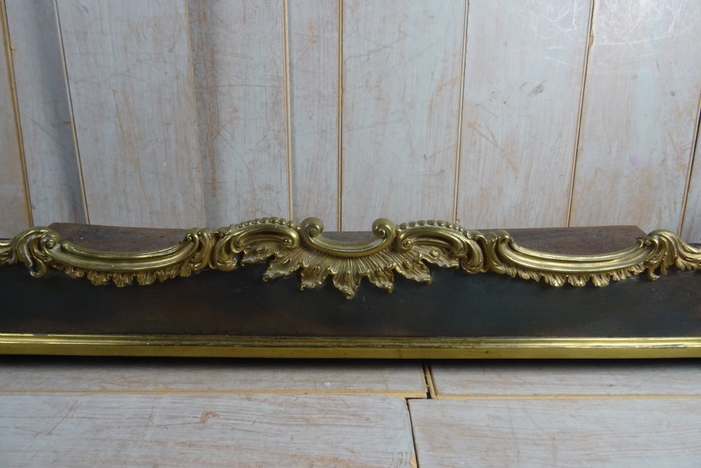 A 19th-century brass and dark steel fireplace fender featuring cast brass Rococo scrollwork and shell motifs along the top rail and corner feet. View III