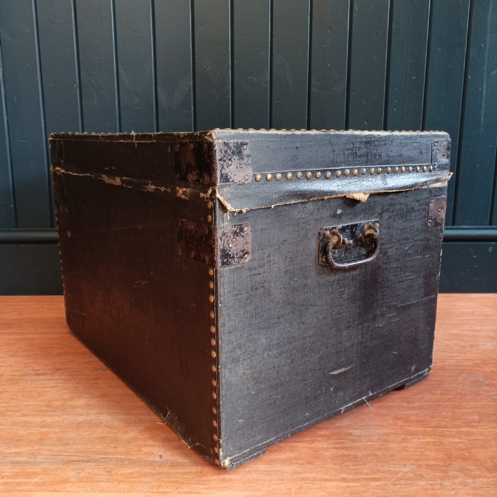 A rectangular dark brown leather campaign trunk featuring brass studding along the lid edges, metal corner brackets, and drop handles. View II