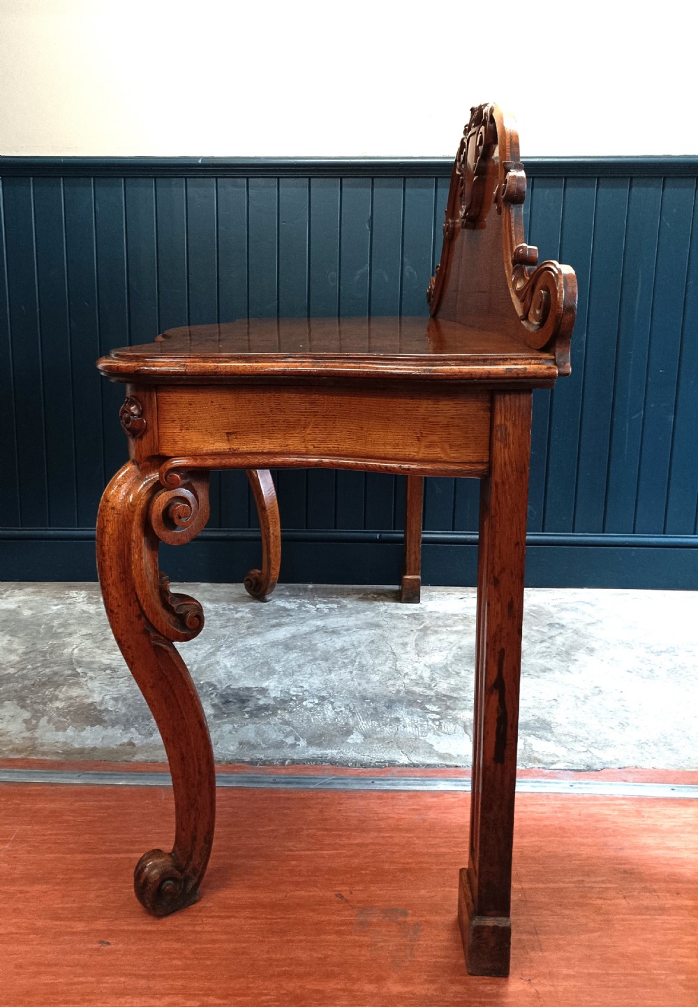 A carved mid-19th-century Victorian oak hall console table featuring scrolled cabriole legs, a central acanthus leaf apron, and a raised gallery back with a carved shield crest. View V