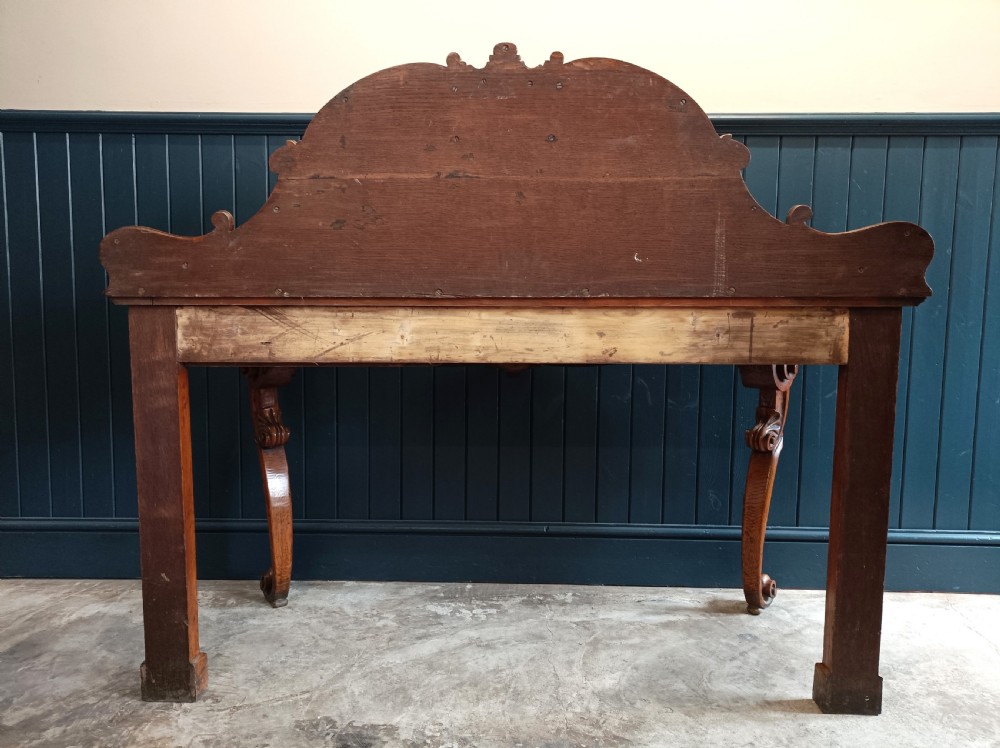 A carved mid-19th-century Victorian oak hall console table featuring scrolled cabriole legs, a central acanthus leaf apron, and a raised gallery back with a carved shield crest. View VII