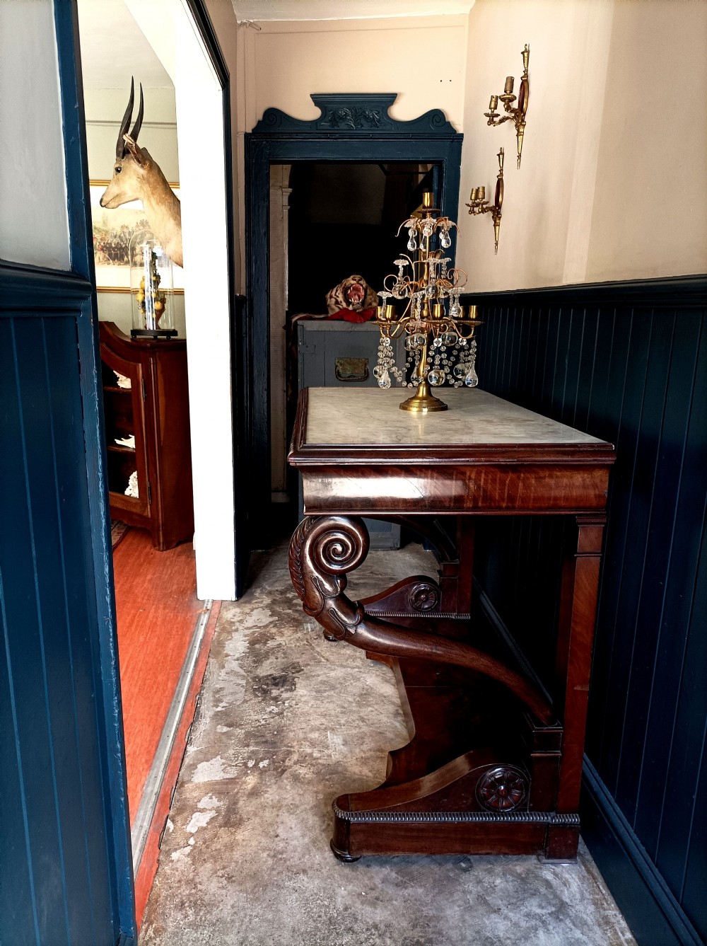 An Italian mahogany console table featuring S-scroll carved legs, a low plinth base, and a grey and white marble top.