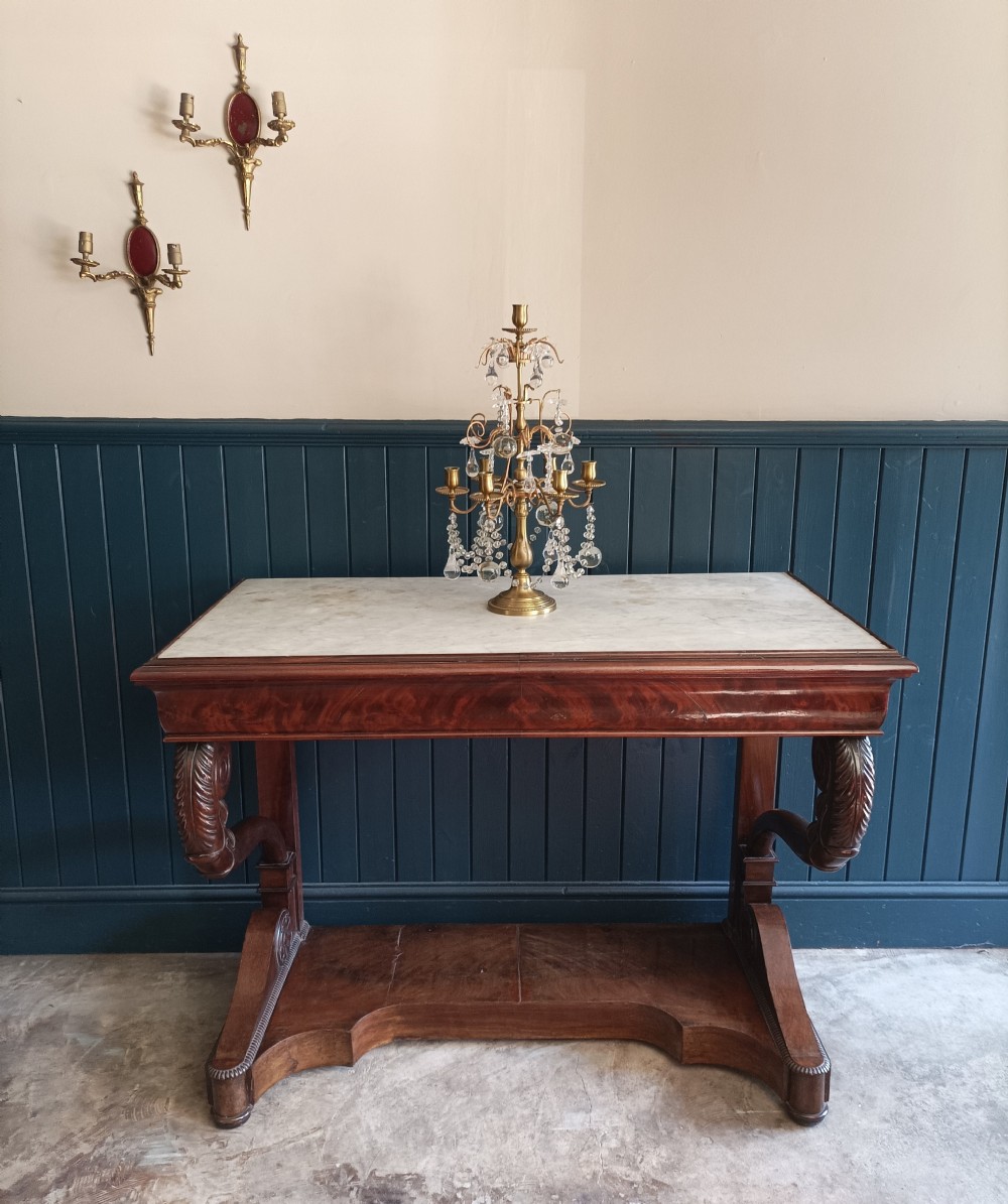 An Italian mahogany console table featuring S-scroll carved legs, a low plinth base, and a grey and white marble top. View IX