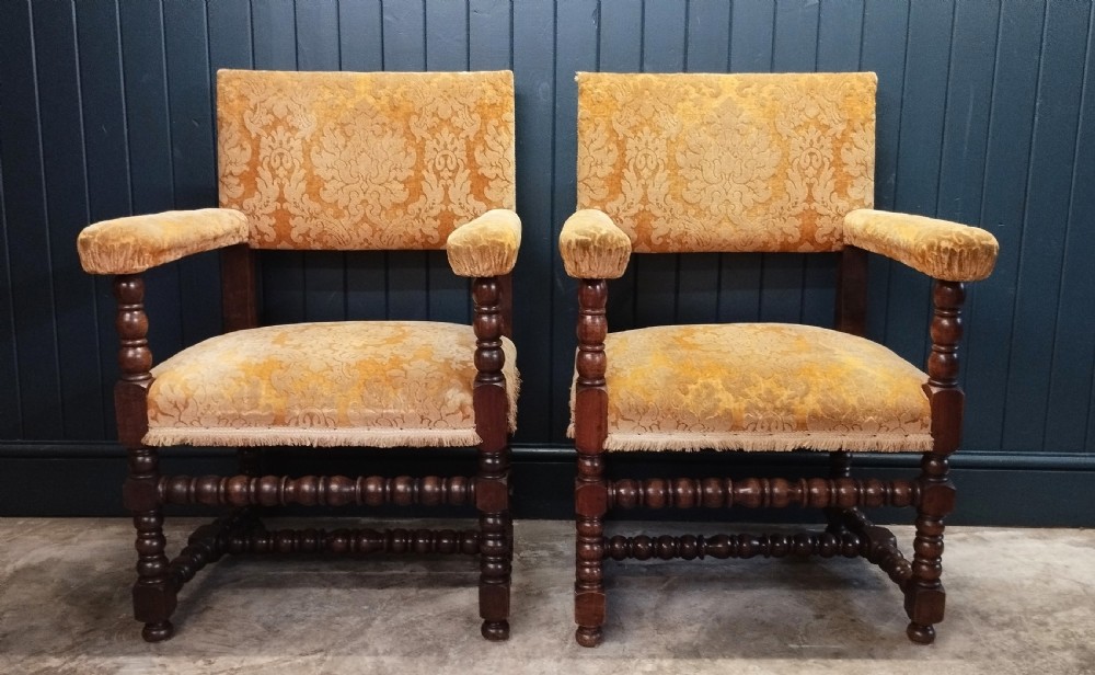 A pair of Italian style open armchairs with dark bobbin turned frames and gold damask upholstery with fringe trim.