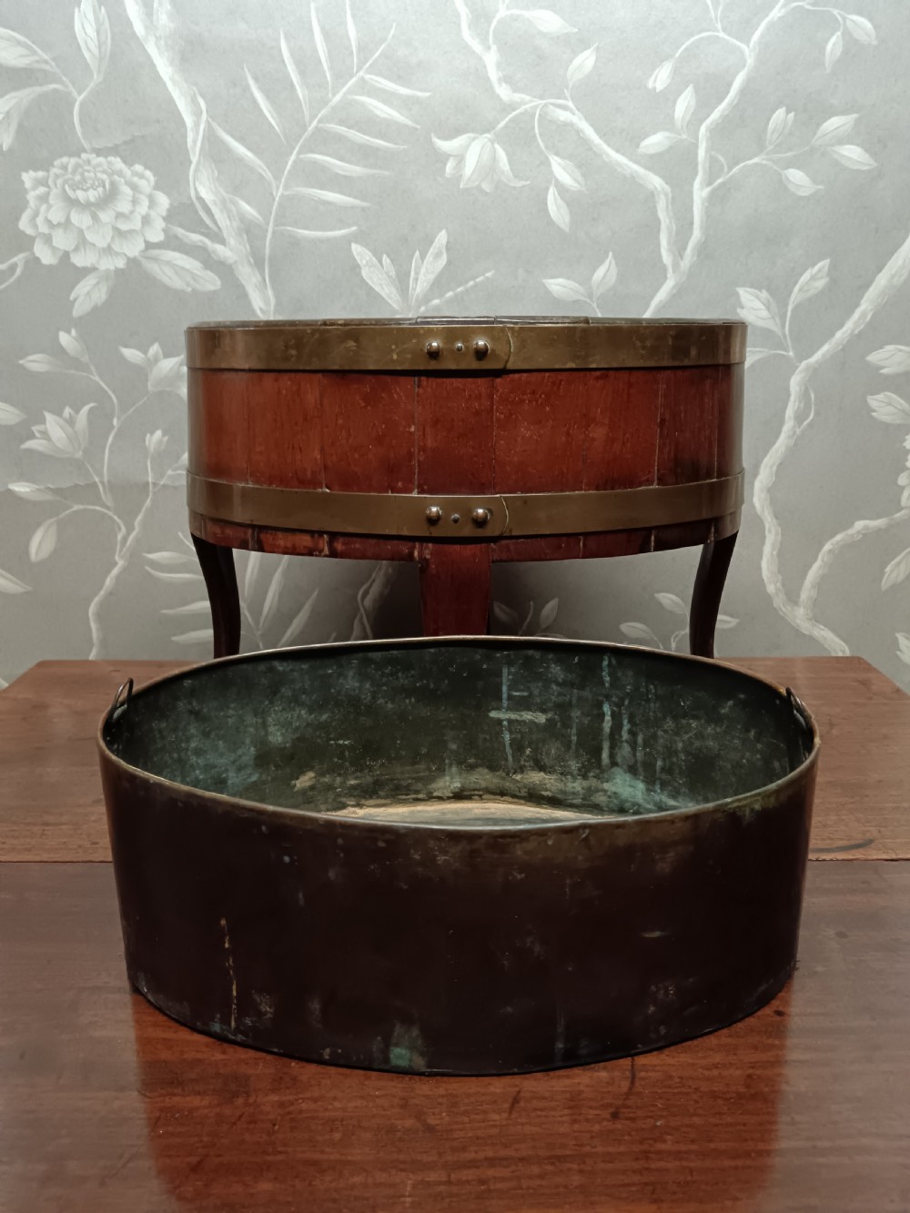 A circular coopered mahogany wine cooler featuring two brass bands and four short splayed legs, containing a metal lining. View III
