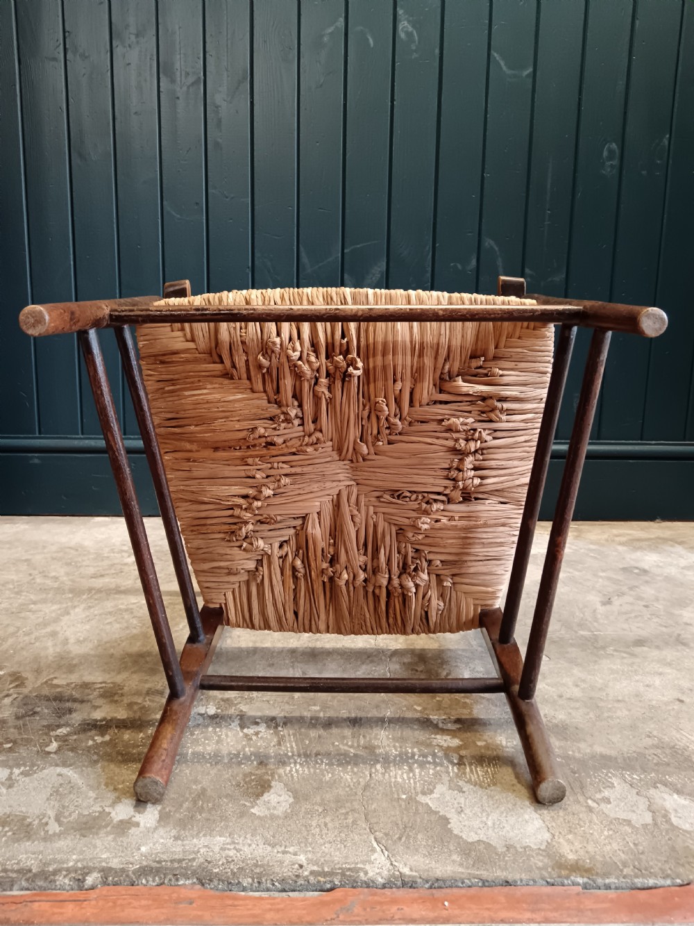 An Arts and Crafts dark wooden ladder back armchair featuring curved armrests and a woven rush seat. View X