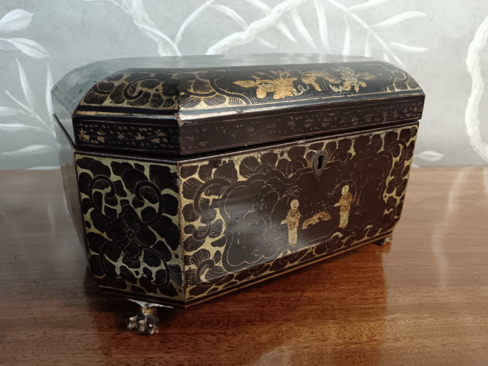 An open octagonal dark lacquer tea box decorated with gilded Chinese motifs containing two engraved pewter metal canisters. View II