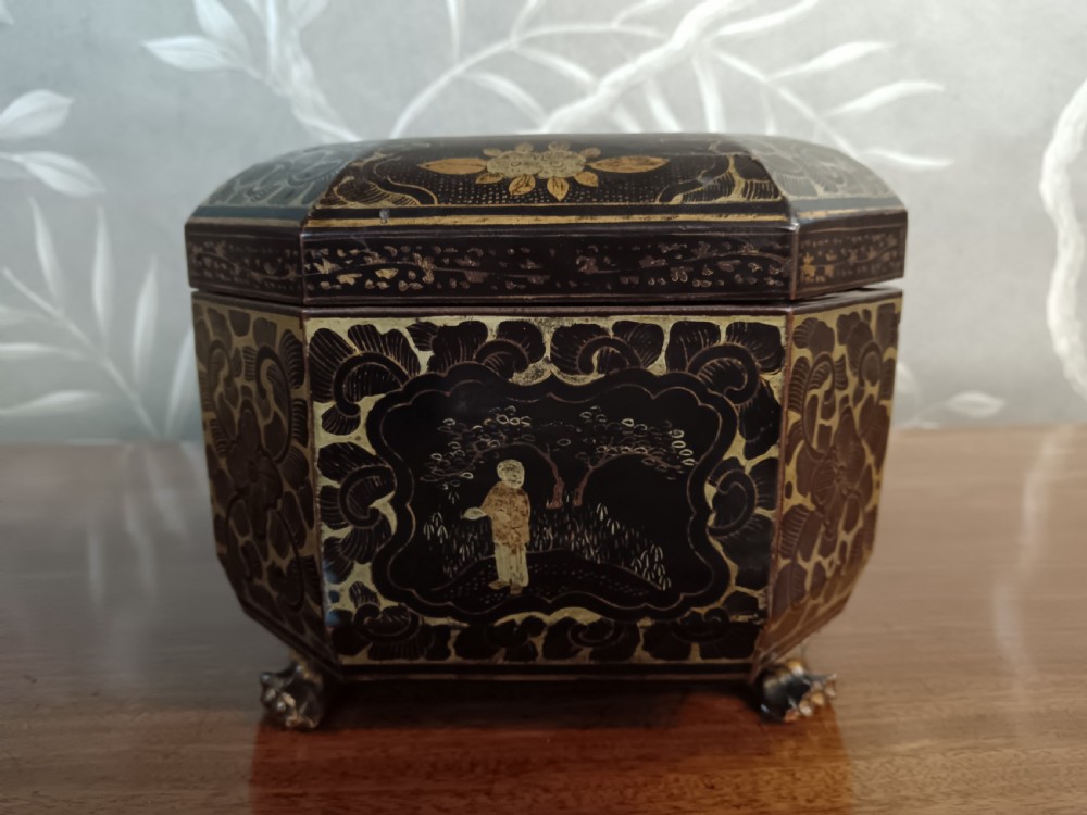 An open octagonal dark lacquer tea box decorated with gilded Chinese motifs containing two engraved pewter metal canisters. View III