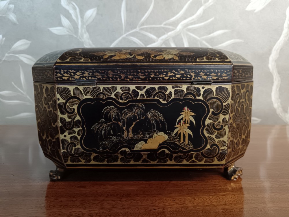 An open octagonal dark lacquer tea box decorated with gilded Chinese motifs containing two engraved pewter metal canisters. View V