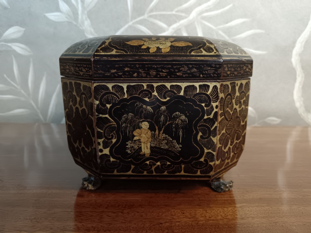 An open octagonal dark lacquer tea box decorated with gilded Chinese motifs containing two engraved pewter metal canisters. View VI