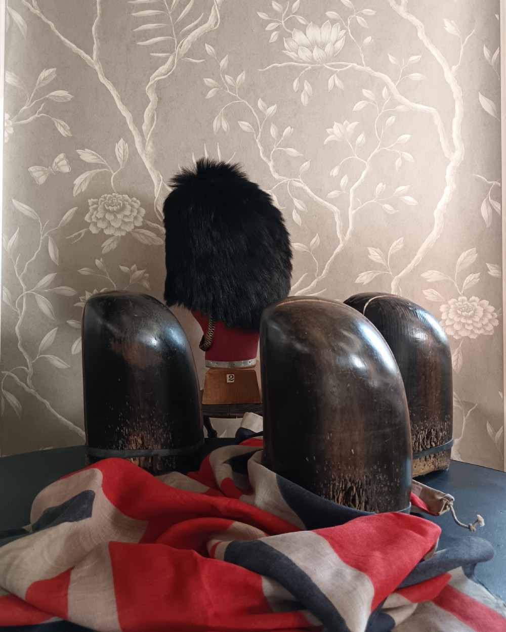 Three tall carved dark wooden millinery hat blocks with sloping rounded tops arranged in a row on a surface. View XI