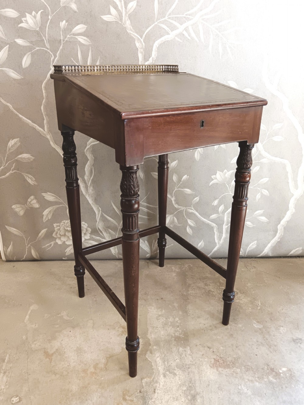 A dark mahogany Regency ladys writing desk featuring turned reeded legs, a single drawer with a keyhole escutcheon, a leather inset top, and a brass gallery along the rear edge. View III