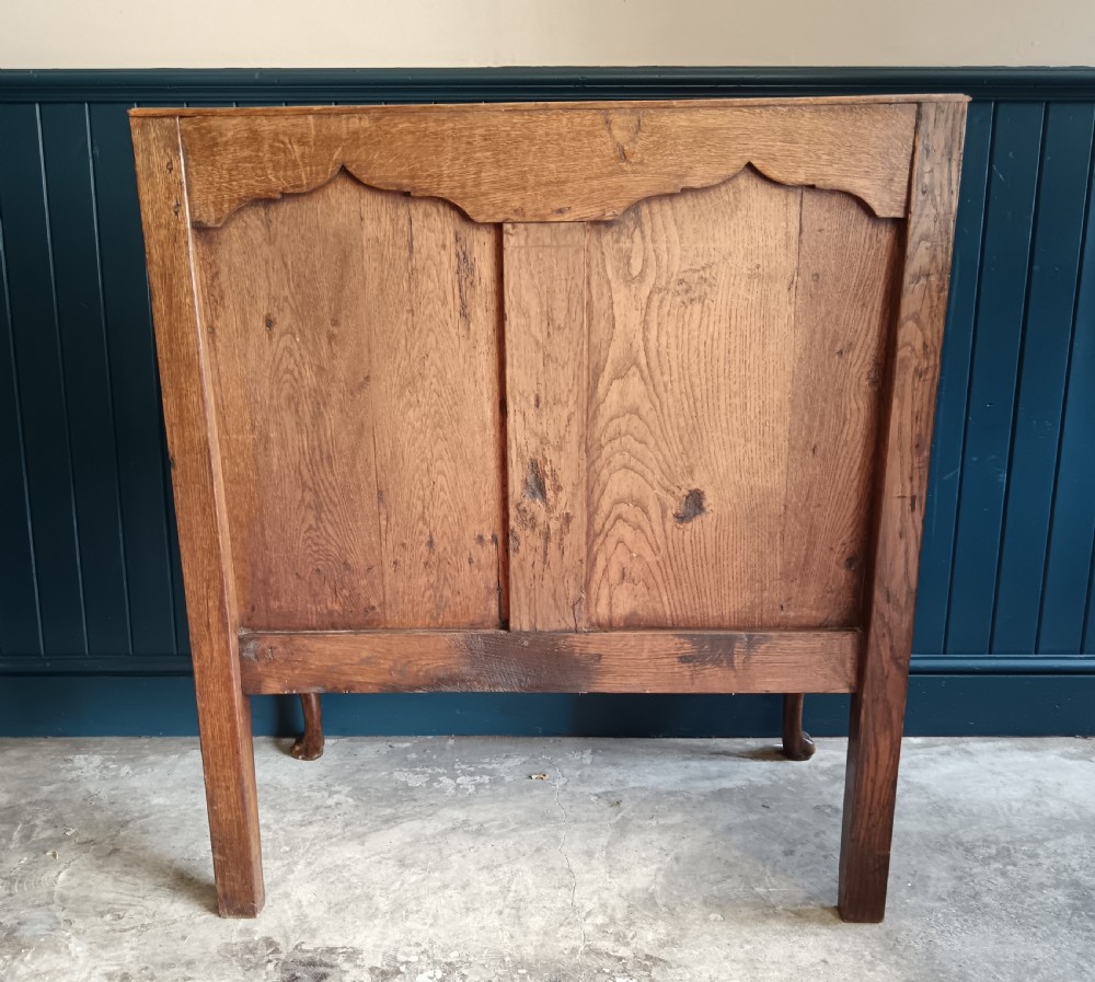A Georgian oak two-seater settle bench with a twin-panelled back, cabriole front legs, and a blue patterned seat. View V