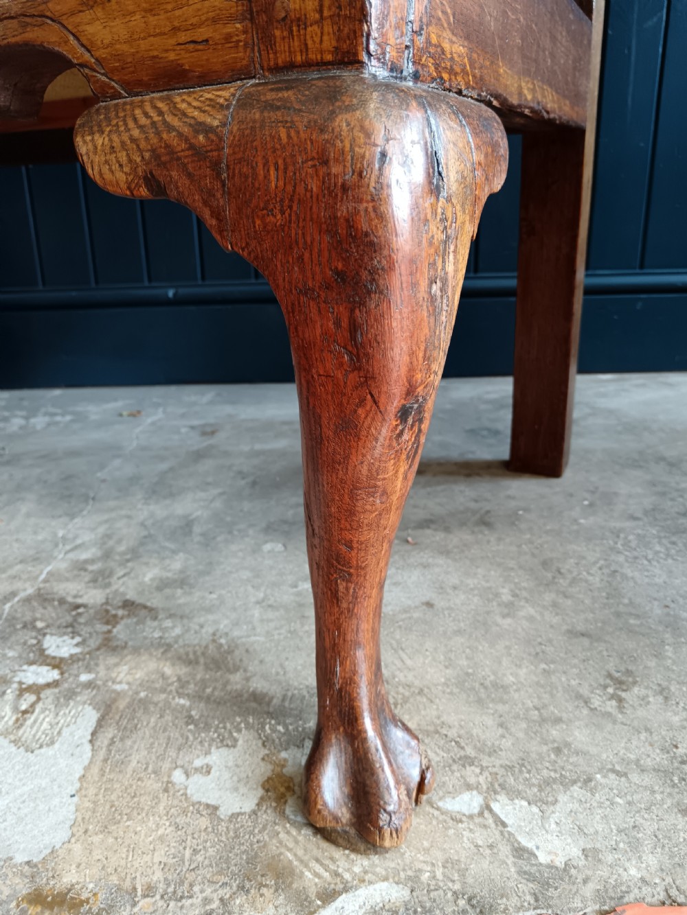 A Georgian oak two-seater settle bench with a twin-panelled back, cabriole front legs, and a blue patterned seat. View VI