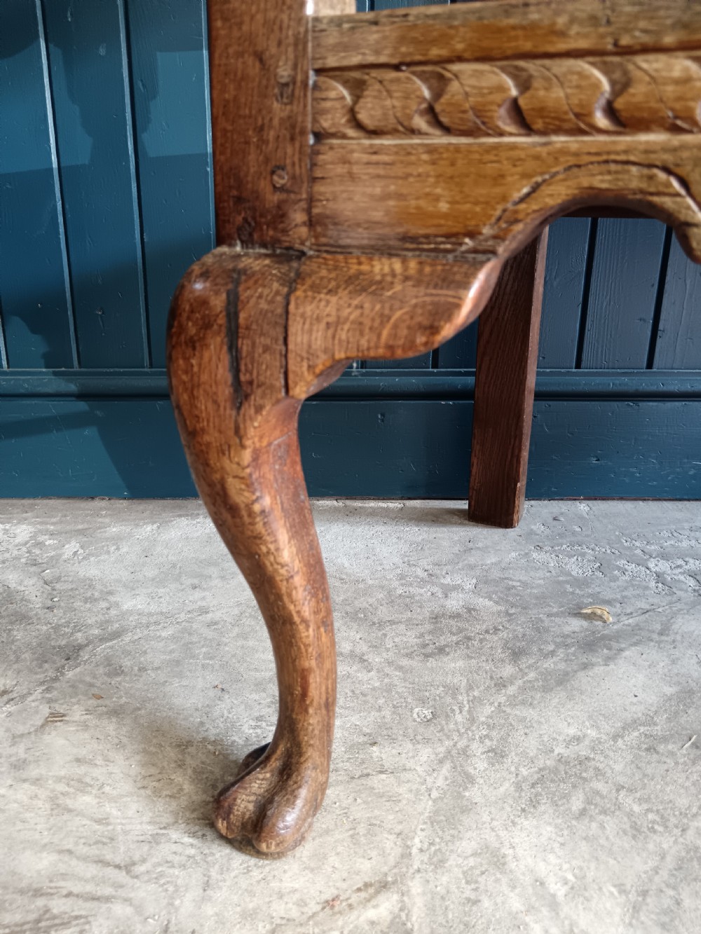 A Georgian oak two-seater settle bench with a twin-panelled back, cabriole front legs, and a blue patterned seat. View VII