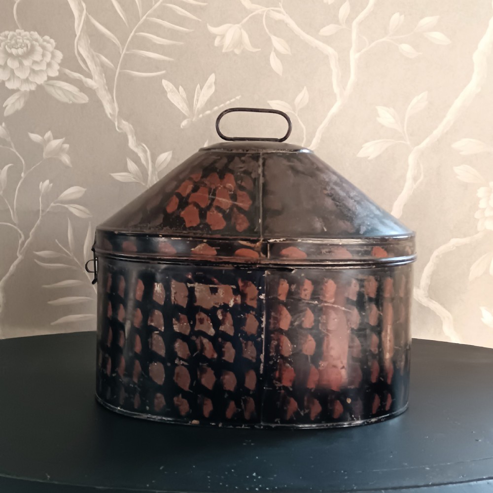 A dark painted antique tin hat box with a domed lid, top carrying handle, and hand-painted pattern. View VIII