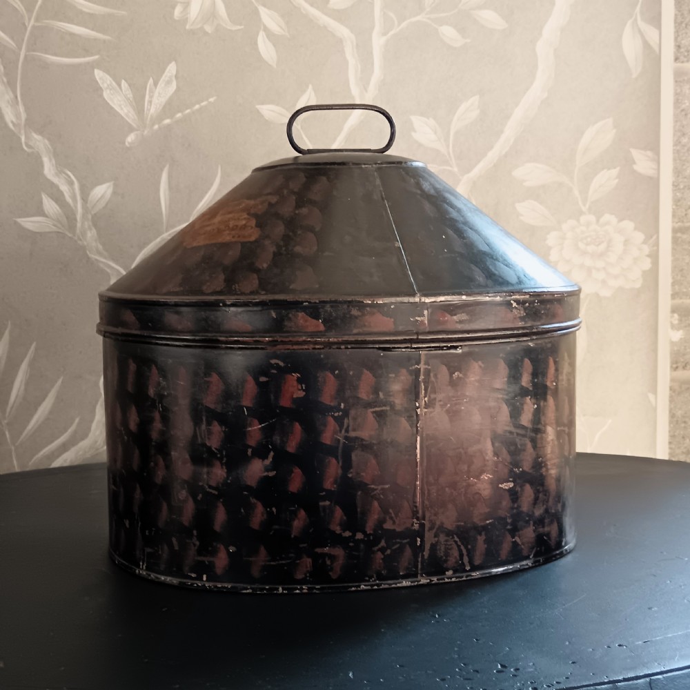A dark painted antique tin hat box with a domed lid, top carrying handle, and hand-painted pattern. View IX