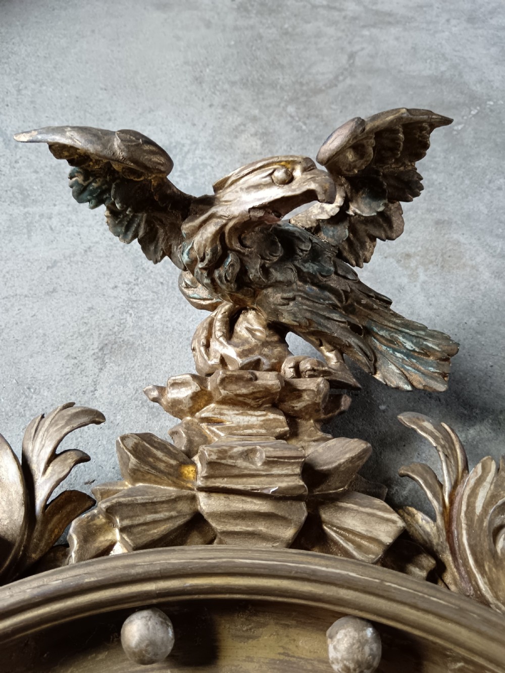 A circular Regency style giltwood convex wall mirror topped with a carved eagle cresting and featuring twin candle sconces. View V