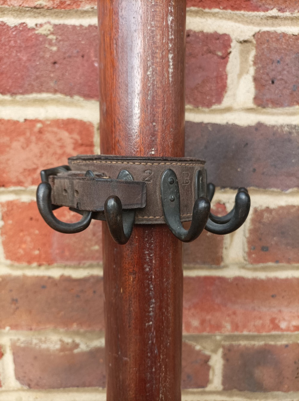 A thick dark brown leather strap with an adjustable buckle and multiple curved black iron hooks riveted around its exterior. View II