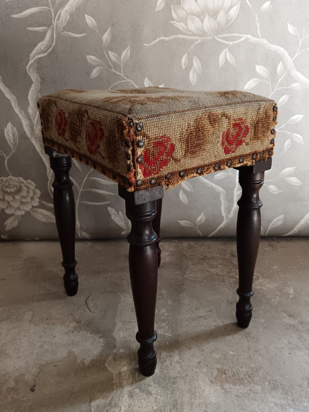 A rectangular Victorian mahogany stool featuring dark turned legs and a tapestry top with red floral rose motifs bordered by brass studs. View V