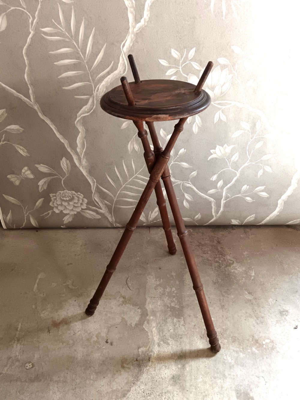 A dark brown wooden campaign washbowl stand featuring turned faux-bamboo tripod legs and vertical pegs around a circular top. View II