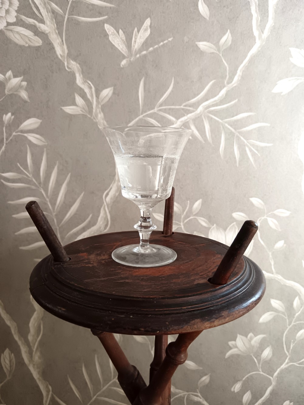 A dark brown wooden campaign washbowl stand featuring turned faux-bamboo tripod legs and vertical pegs around a circular top. View III