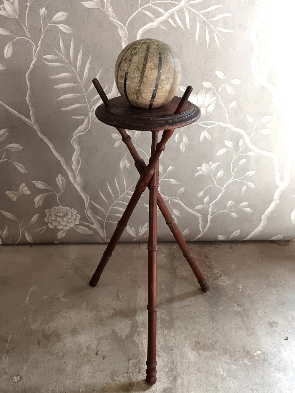 A dark brown wooden campaign washbowl stand featuring turned faux-bamboo tripod legs and vertical pegs around a circular top. View IV