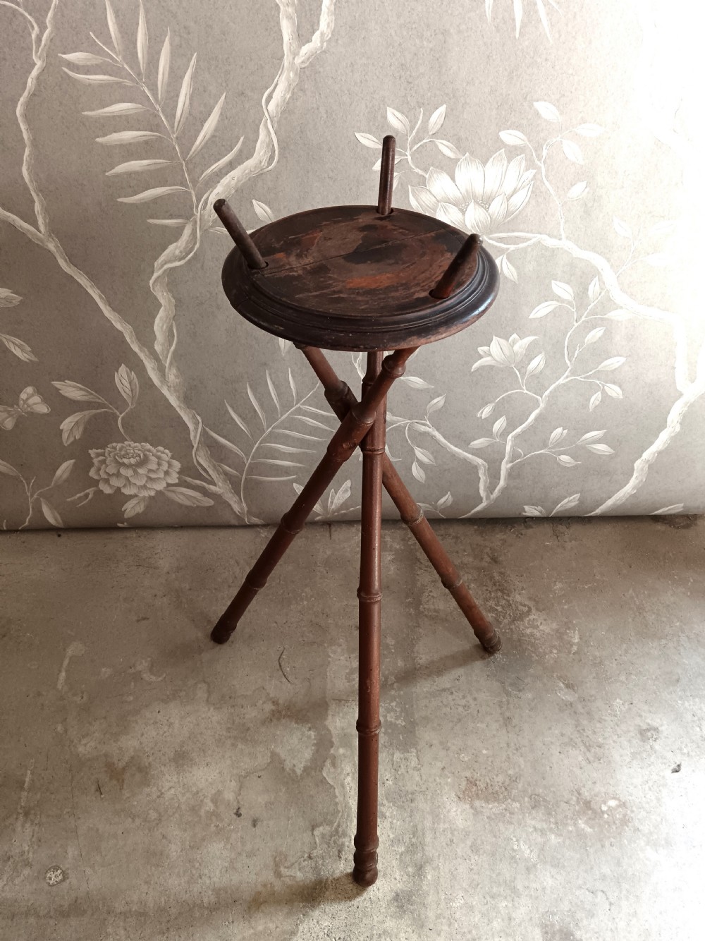 A dark brown wooden campaign washbowl stand featuring turned faux-bamboo tripod legs and vertical pegs around a circular top. View VII