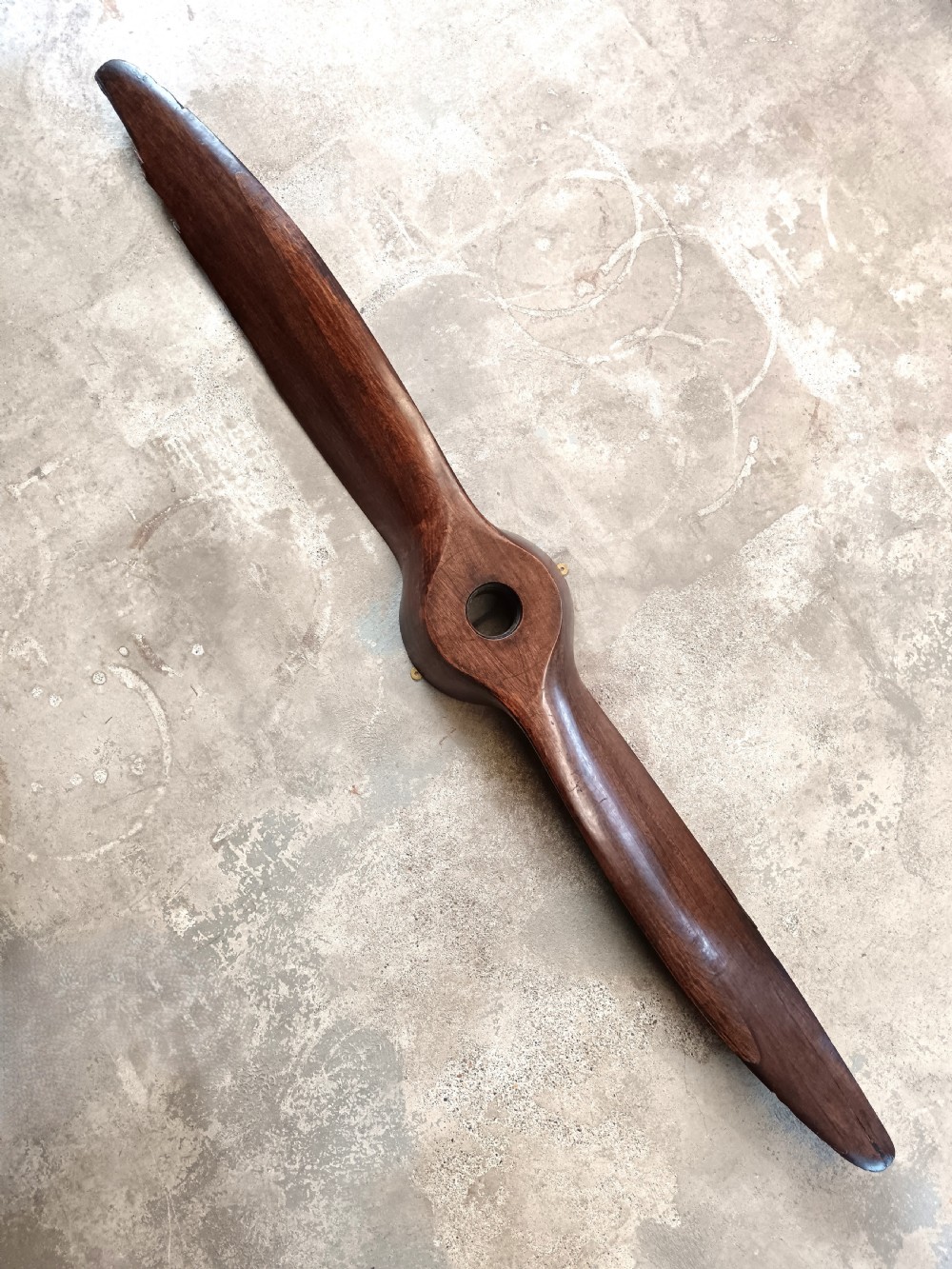 A carved two-blade dark mahogany timber aircraft propeller with a central mounting hole.