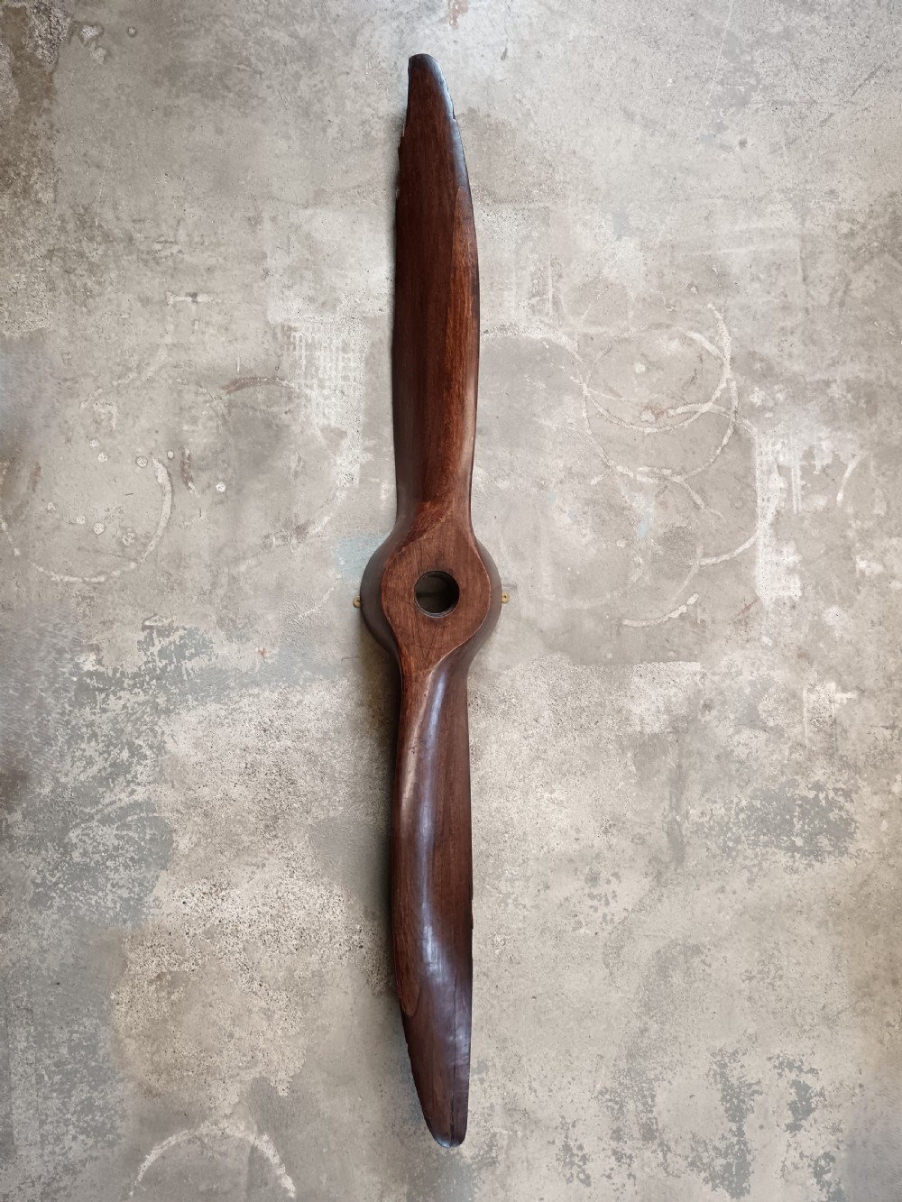 A carved two-blade dark mahogany timber aircraft propeller with a central mounting hole. View V