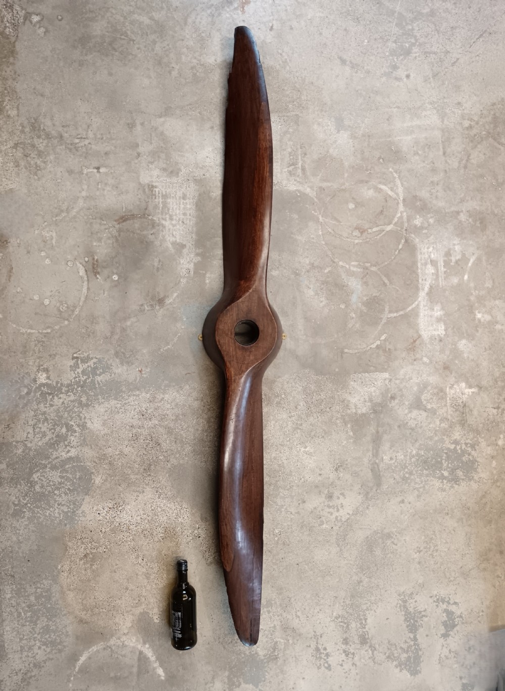 A carved two-blade dark mahogany timber aircraft propeller with a central mounting hole. View III