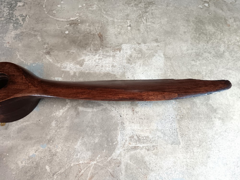 A carved two-blade dark mahogany timber aircraft propeller with a central mounting hole. View VI