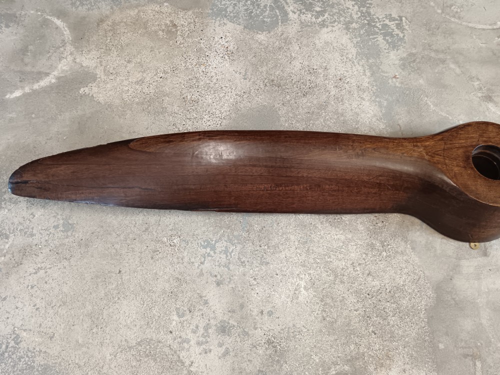 A carved two-blade dark mahogany timber aircraft propeller with a central mounting hole. View VII
