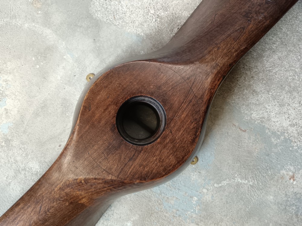 A carved two-blade dark mahogany timber aircraft propeller with a central mounting hole. View IX