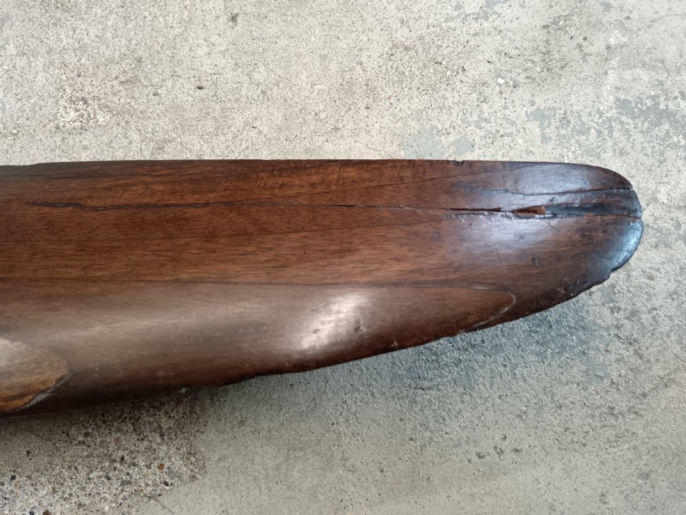 A carved two-blade dark mahogany timber aircraft propeller with a central mounting hole. View XII