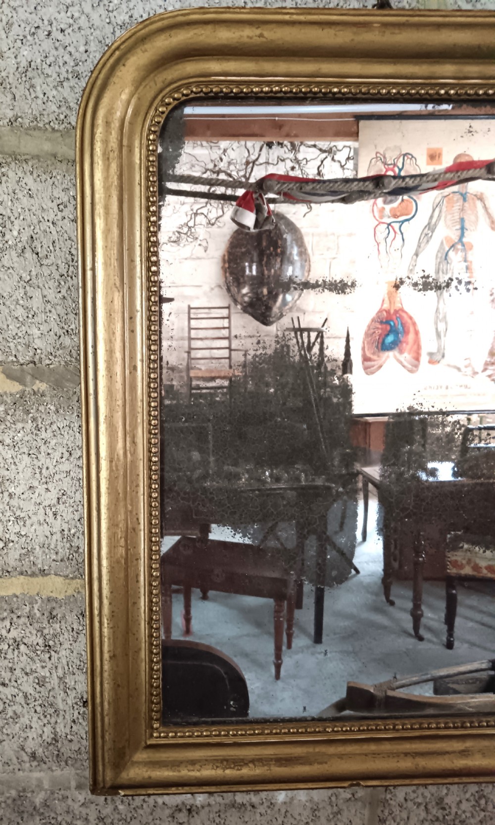 A 19th-century French wall mirror featuring a rectangular gilded frame with rounded upper corners, beaded interior moulding, and heavily foxed glass. View VI