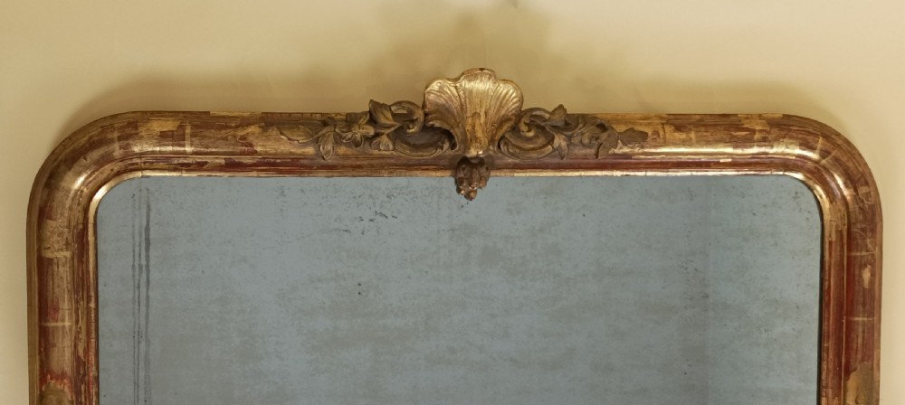 An antique gilded wood overmantel mirror featuring rounded top corners, a central carved shell crest, and scroll bracket feet. View II