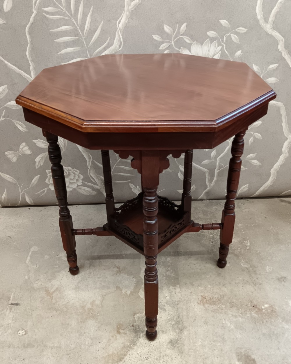 An octagonal dark walnut side table featuring turned legs, a lower shelf with decorative carved fretwork, and an eight-sided bevelled top. View II